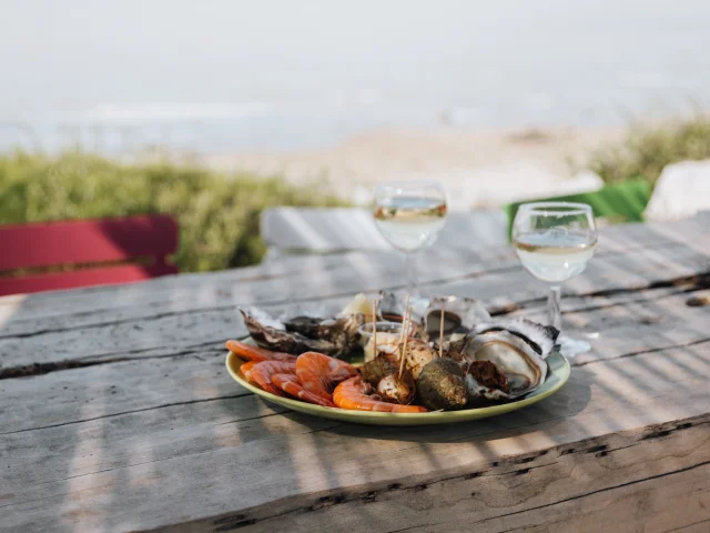 Un plateau de fruits de mer avec des verres de vin sur une table en bois.