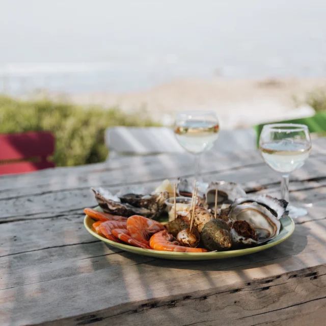 Un plateau de fruits de mer avec des verres de vin sur une table en bois.