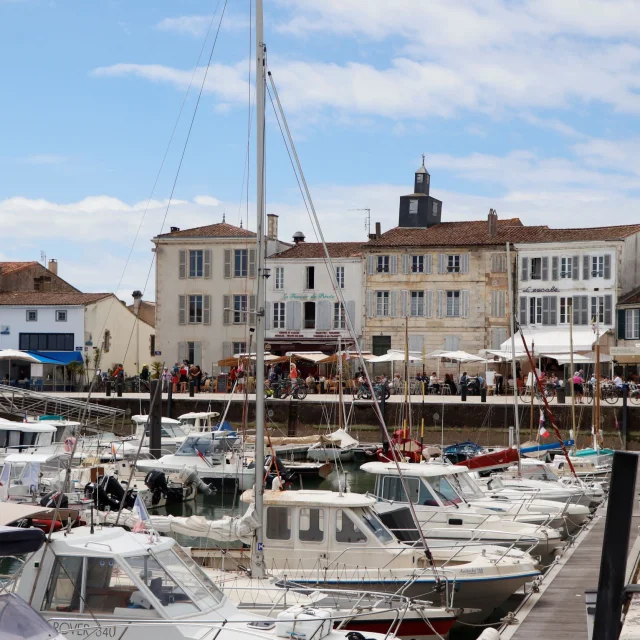 Vue sur le port de La Flotte avec des bateaux amarrés et des bâtiments en arrière-plan.