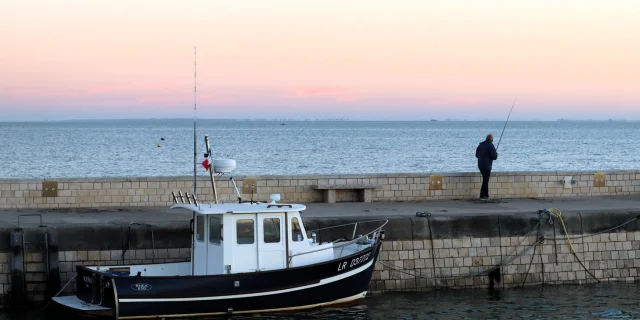 Un pêcheur sur le quai de Rivedoux avec un bateau amarré à proximité.