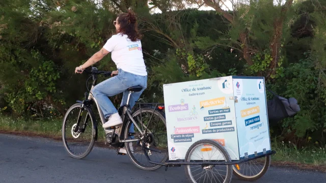 Personne circulant à vélo avec une remorque d'accueil mobile attachée à l'arrière.