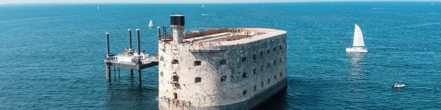 Vue aérienne du fort Boyard entouré par la mer avec des bateaux autour.