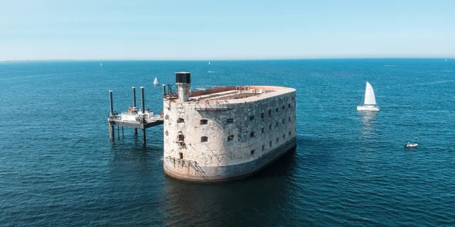 Vue aérienne du fort Boyard entouré par la mer avec des bateaux autour.