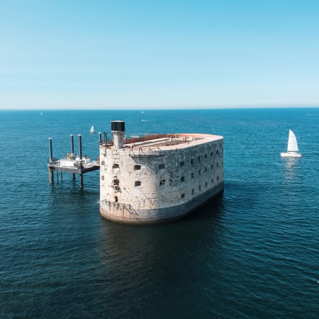 Vue aérienne du fort Boyard entouré par la mer avec des bateaux autour.