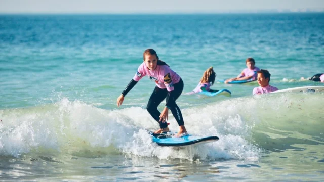 Jeune femme sur une planche de surf attrapant une petite vague.