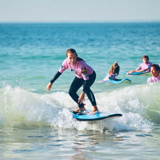 Jeune femme sur une planche de surf attrapant une petite vague.