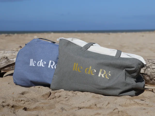 Deux cabas de plage île de Ré posés sur le sable.