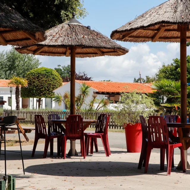 Terrasse avec chaises et parasols au Camping Le Puma