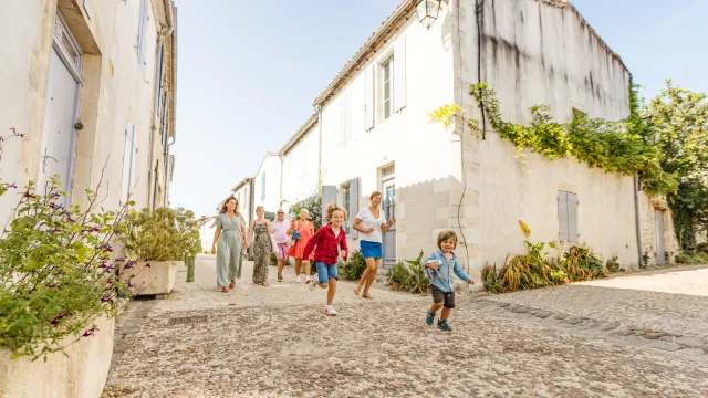 Familles marchant dans une rue pavée et ensoleillée de l'île de Ré