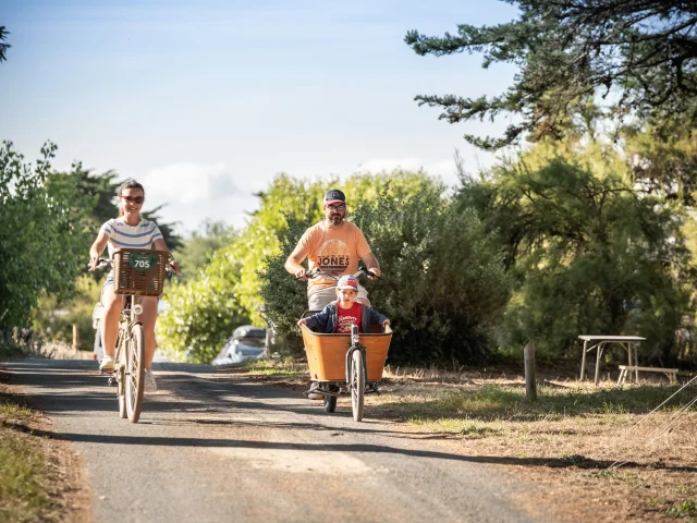 Famille à vélo dans le camping Huttopia Ars-en-Ré