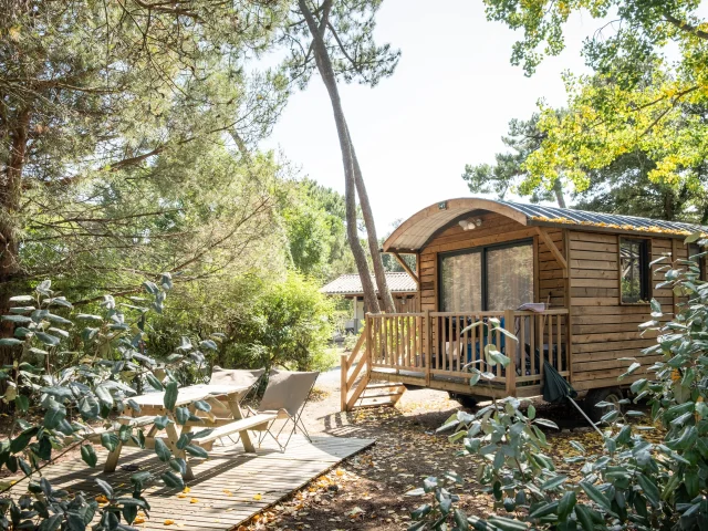 Roulotte en bois au milieu de la forêt au camping Huttopia Chardons Bleus