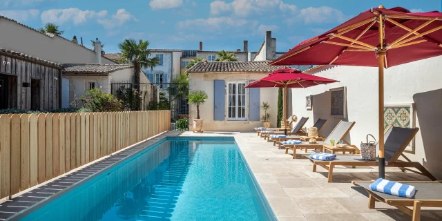 Piscine extérieure avec chaises longues et parasols rouges