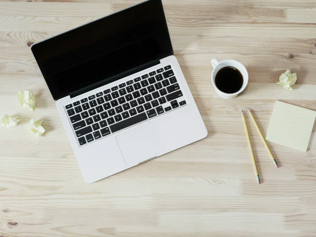 Bureau minimaliste avec un ordinateur portable, café, crayons, et post-it.