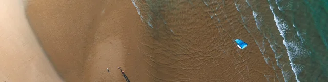 Vue aérienne d'une plage avec un kite surfer.