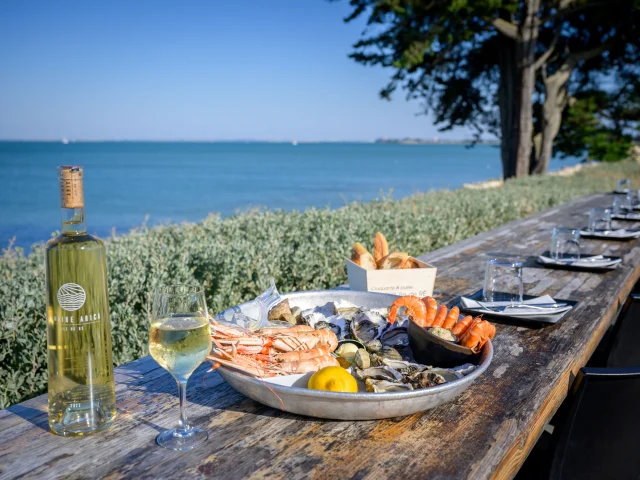 Plateau de fruits de mer et vin blanc sur une table en bord de mer