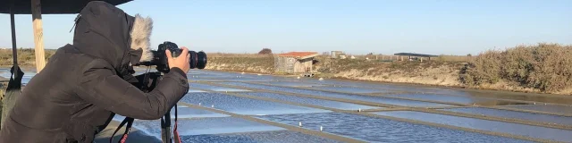 Un photographe en action, prenant des photos des marais salants avec un appareil professionnel.