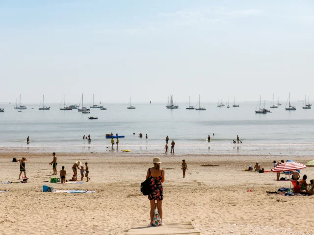 Des vacanciers sur la plage Sud de Rivedoux, avec des bateaux à l'horizon.