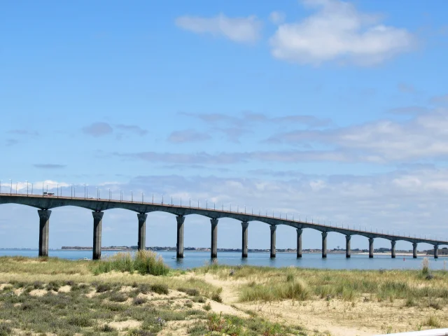 Vue sur le pont de l'île de Ré, s'étendant au-dessus de l'eau sous un ciel bleu.