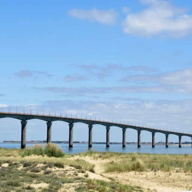 Vue sur le pont de l'île de Ré, s'étendant au-dessus de l'eau sous un ciel bleu.