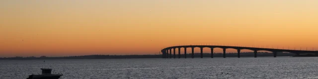 Vue sur le pont de l'île de Ré traversant l'océan au coucher du soleil.