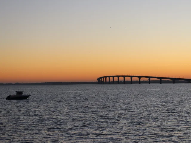 Vue sur le pont de l'île de Ré traversant l'océan au coucher du soleil.